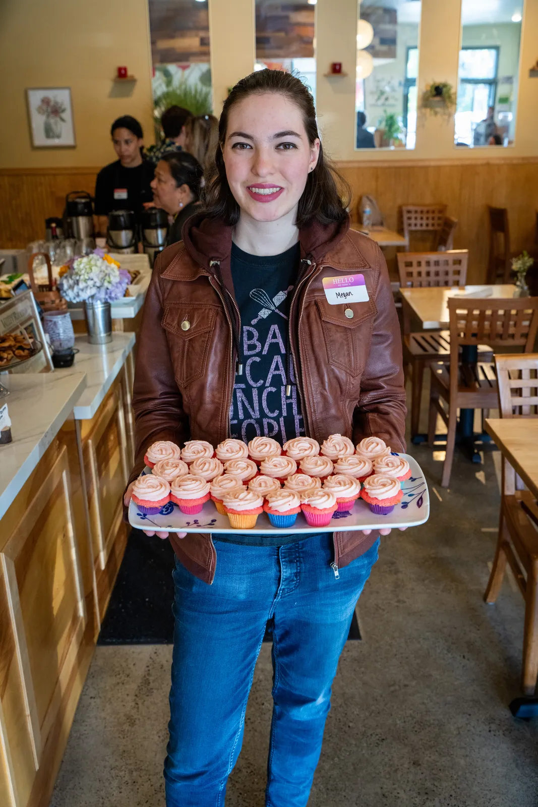 A baker holding a tray of cupcakes