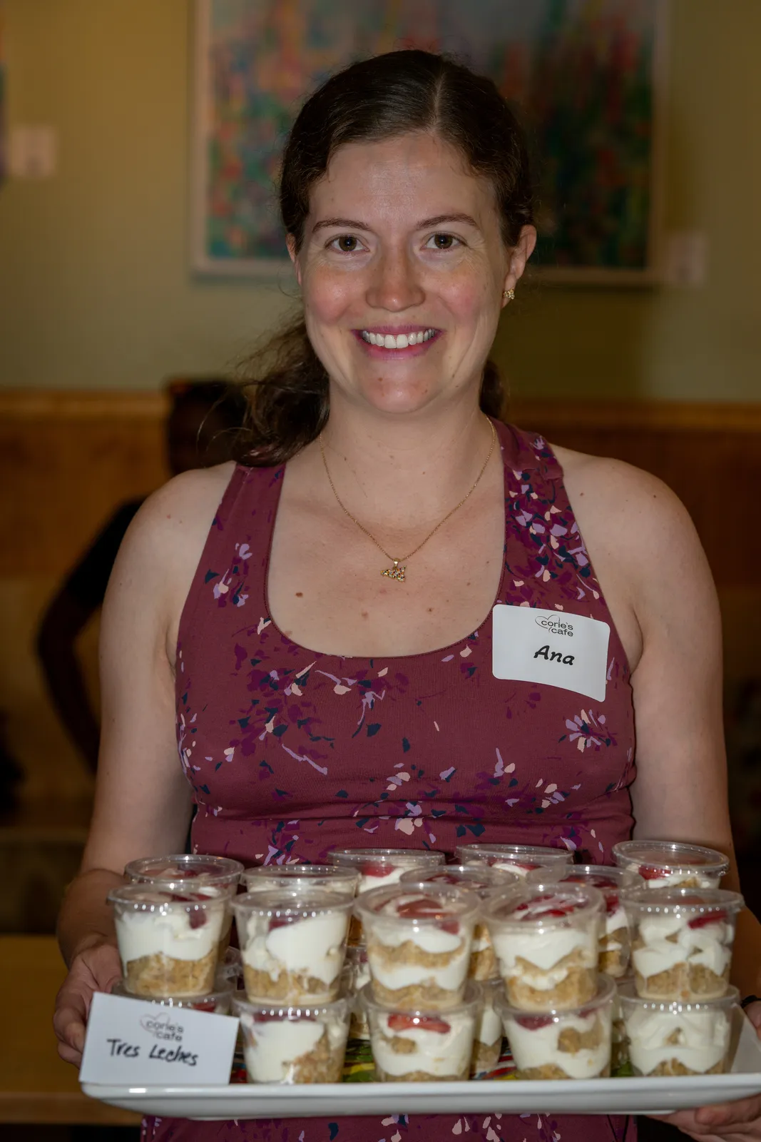 A baker presents a tray of dessert cups