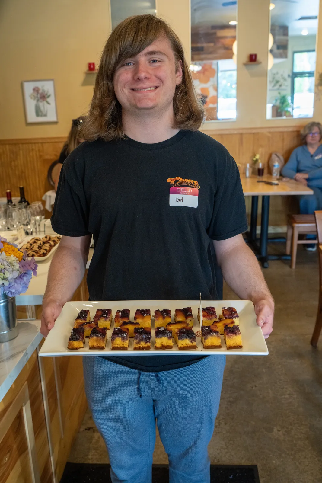A baker presents a tray of mini tarts