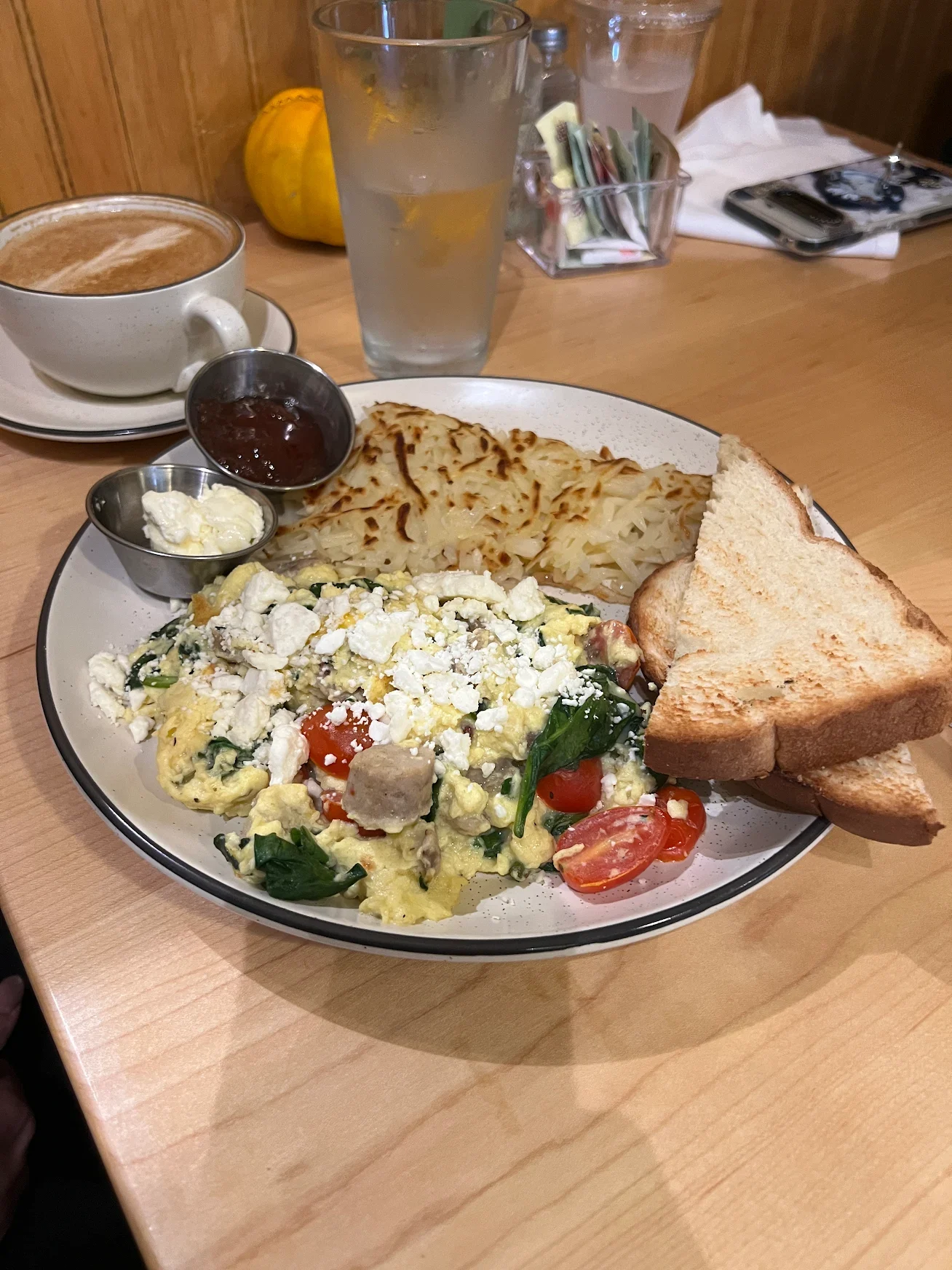 Scrambled eggs with spinach, tomatoes, sausage, feta cheese, served with crispy hashbrowns and toast