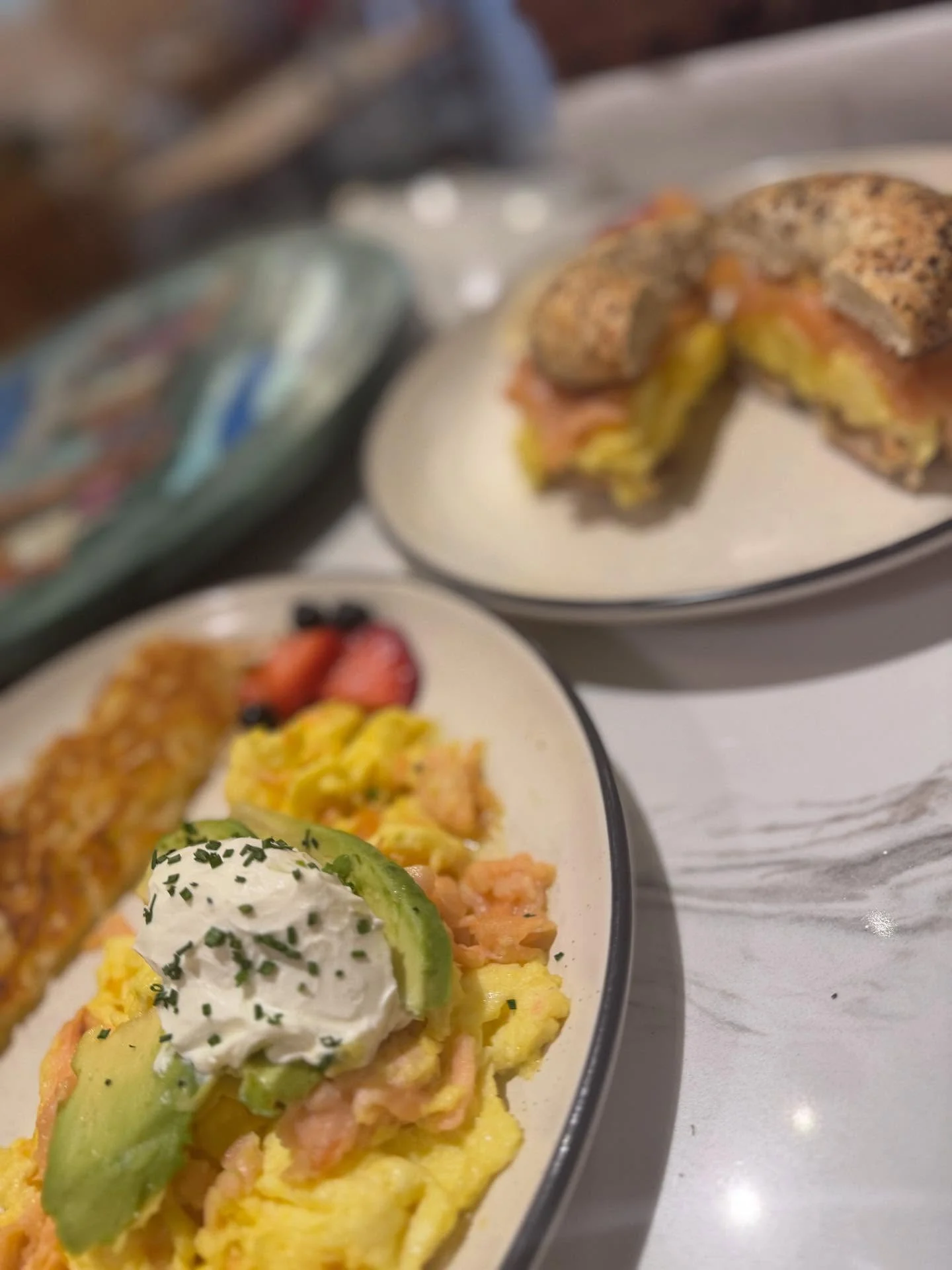 Scrambled eggs with smoked salmon, avocado, and sour cream served with hash browns and fresh fruit