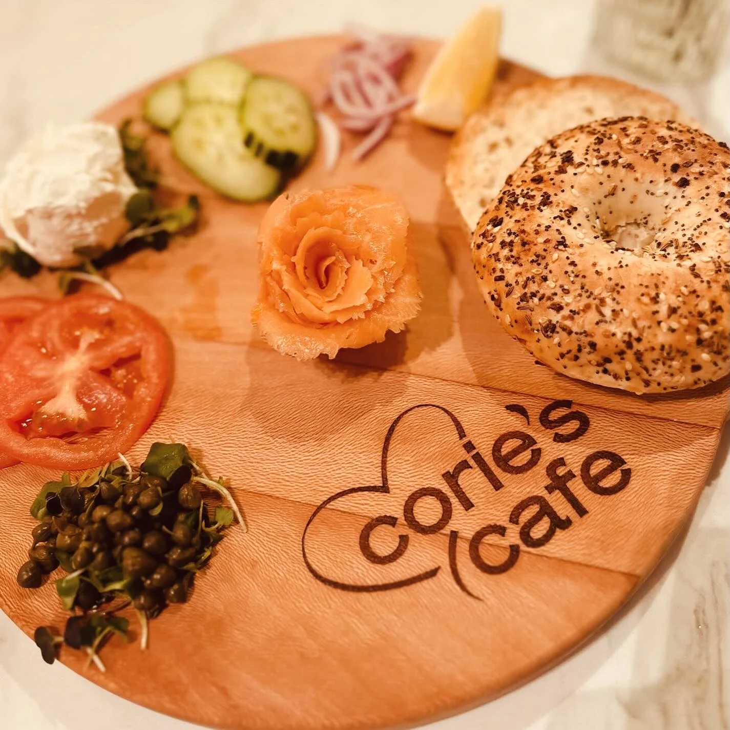 Smoked salmon bagel board with capers, tomatoes, cucumbers, and cream cheese on a wooden serving board