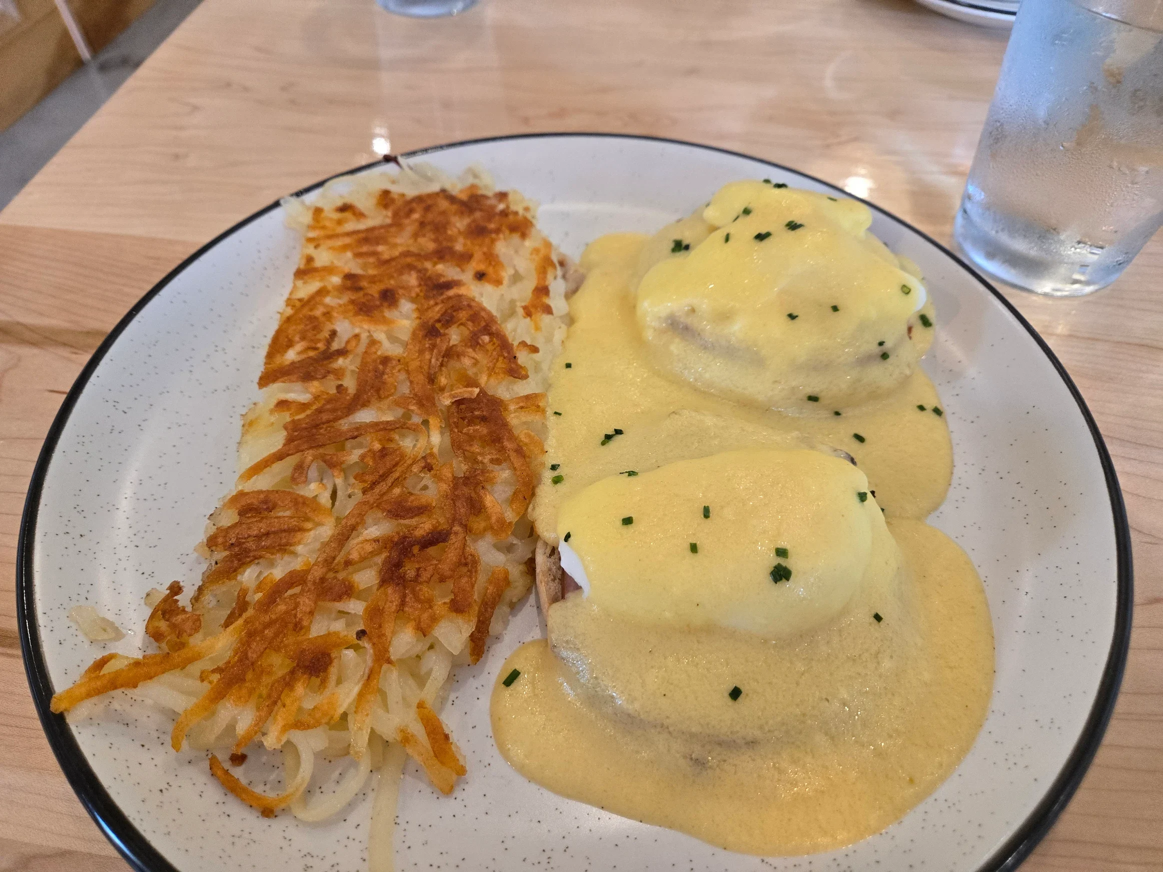 Classic eggs Benedict with poached eggs and hollandaise sauce served alongside crispy hash browns
